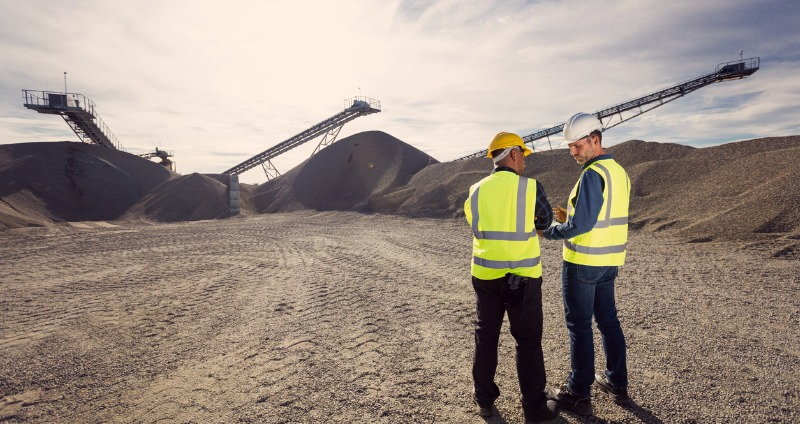 Field workers discussing their next steps on a mine site while using intrinsically safe devices.