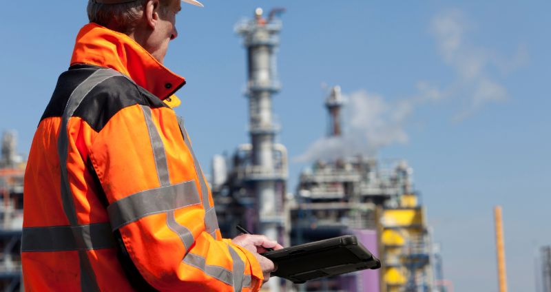 Worker using an intrinsically safe device in a hazardous environment.