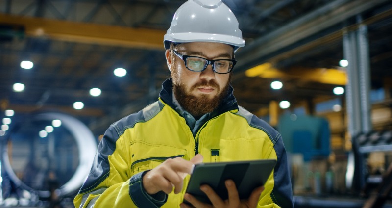 Engineer wearing safety gear holding a rugged laptop