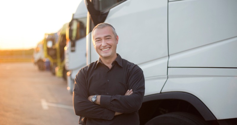 Mature adult male truck driver standing in front of his truck