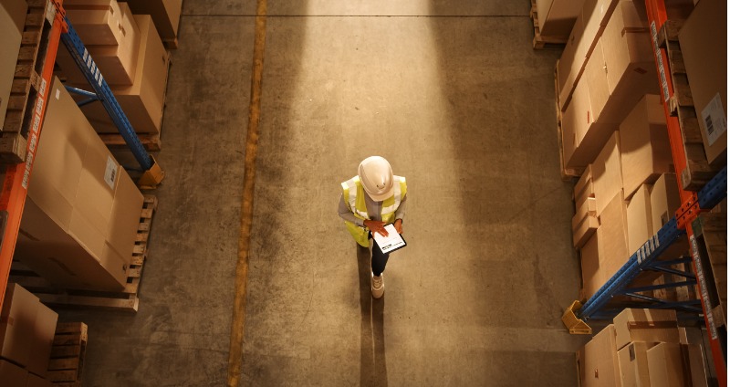A logistics manager using a rugged device while walking through a warehouse.