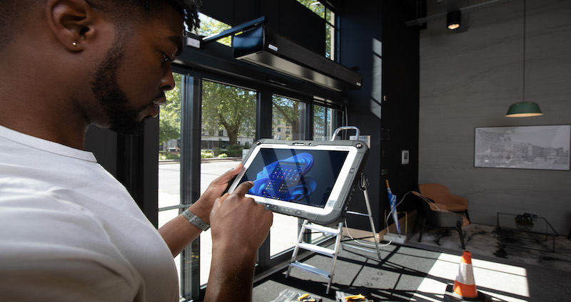 Construction worker inputs data while working on site with a rugged tablet.