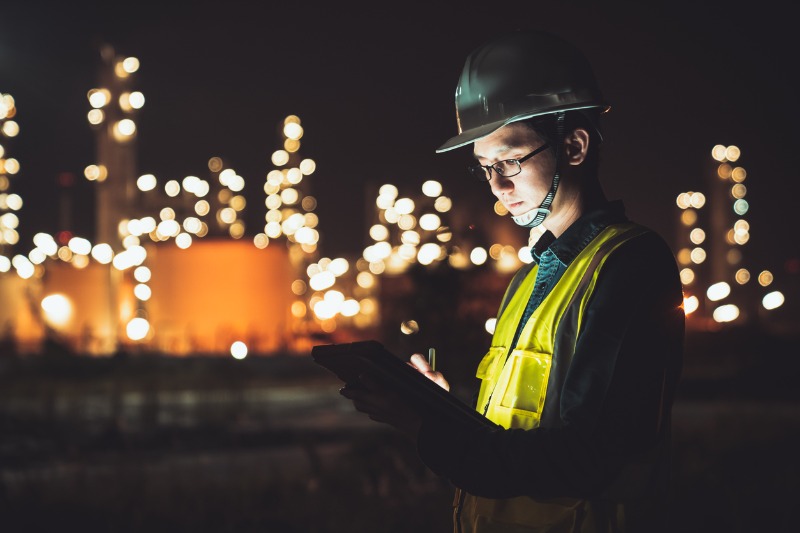man working on his tablet during night shift at an industrial site 